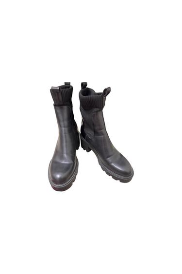 Black chunky-soled, high-leg boots with ribbed detailing, on a white background.