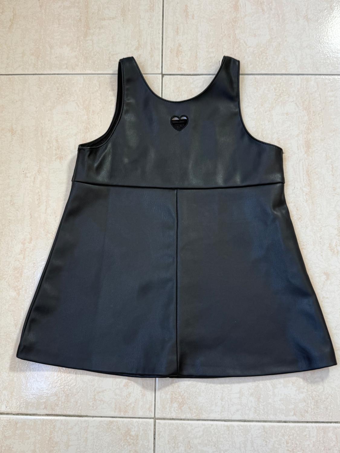 Sleeveless black dress with heart detail on the chest, against a light tiled background.