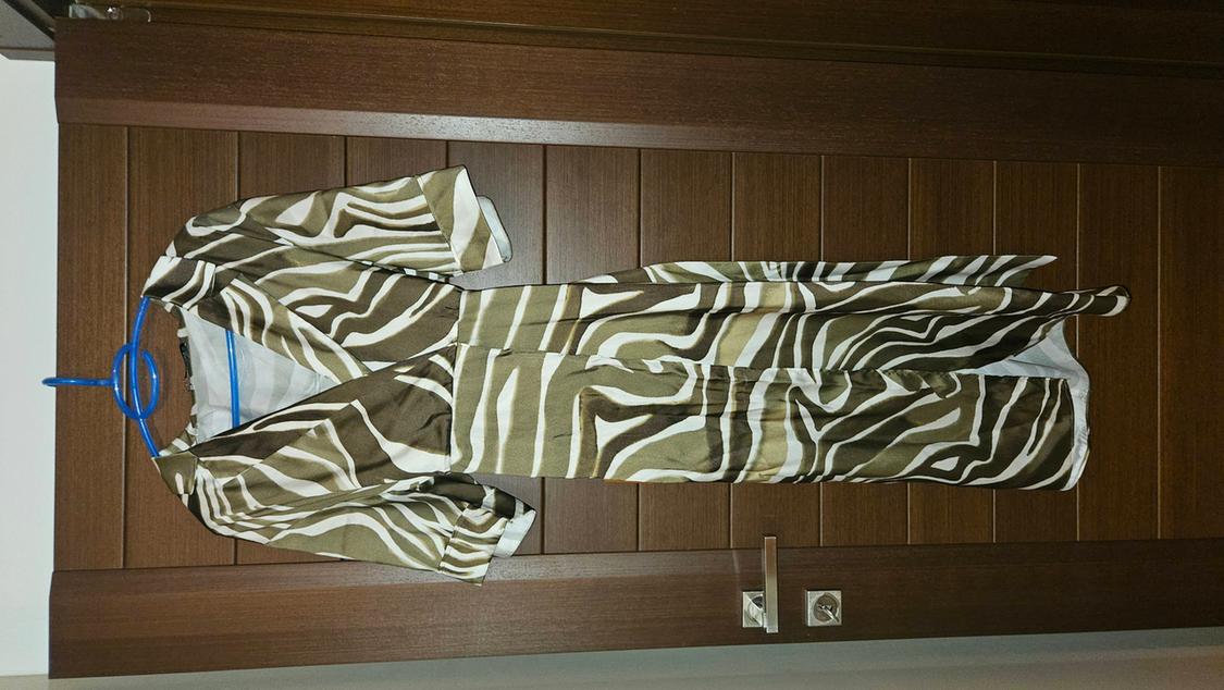Dress hanging on a blue hanger, with a brown and white striped pattern, on a wooden door.