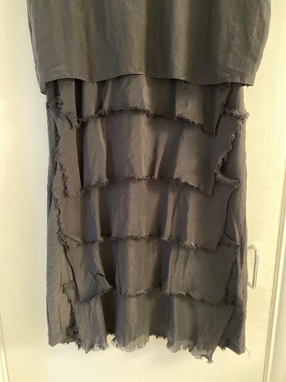 Grey dress with layered, frayed ruffles, hanging over a white door.