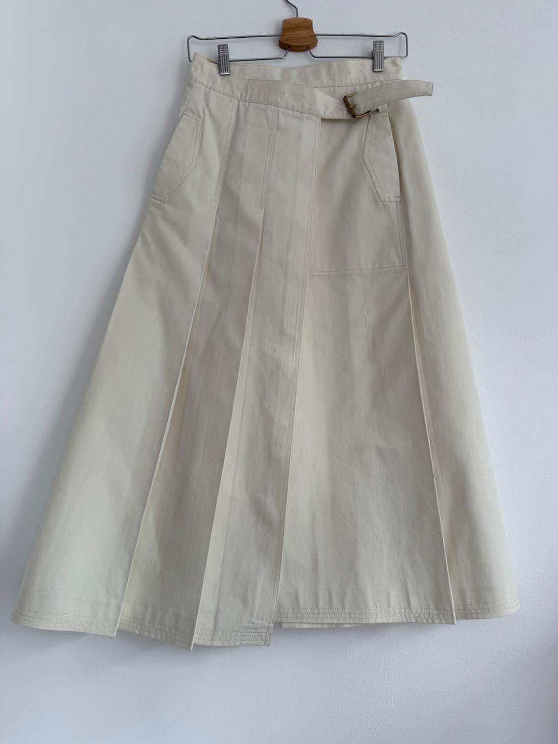 Beige midi skirt with pleats and belt, hanging on a wooden hanger against a white background.
