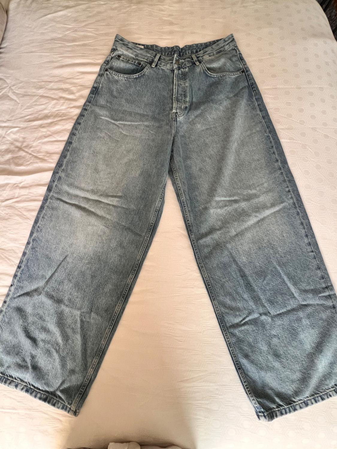 Light-wash light-blue wide-leg jeans laid out on a white sheet. Casual, relaxed-style photograph.