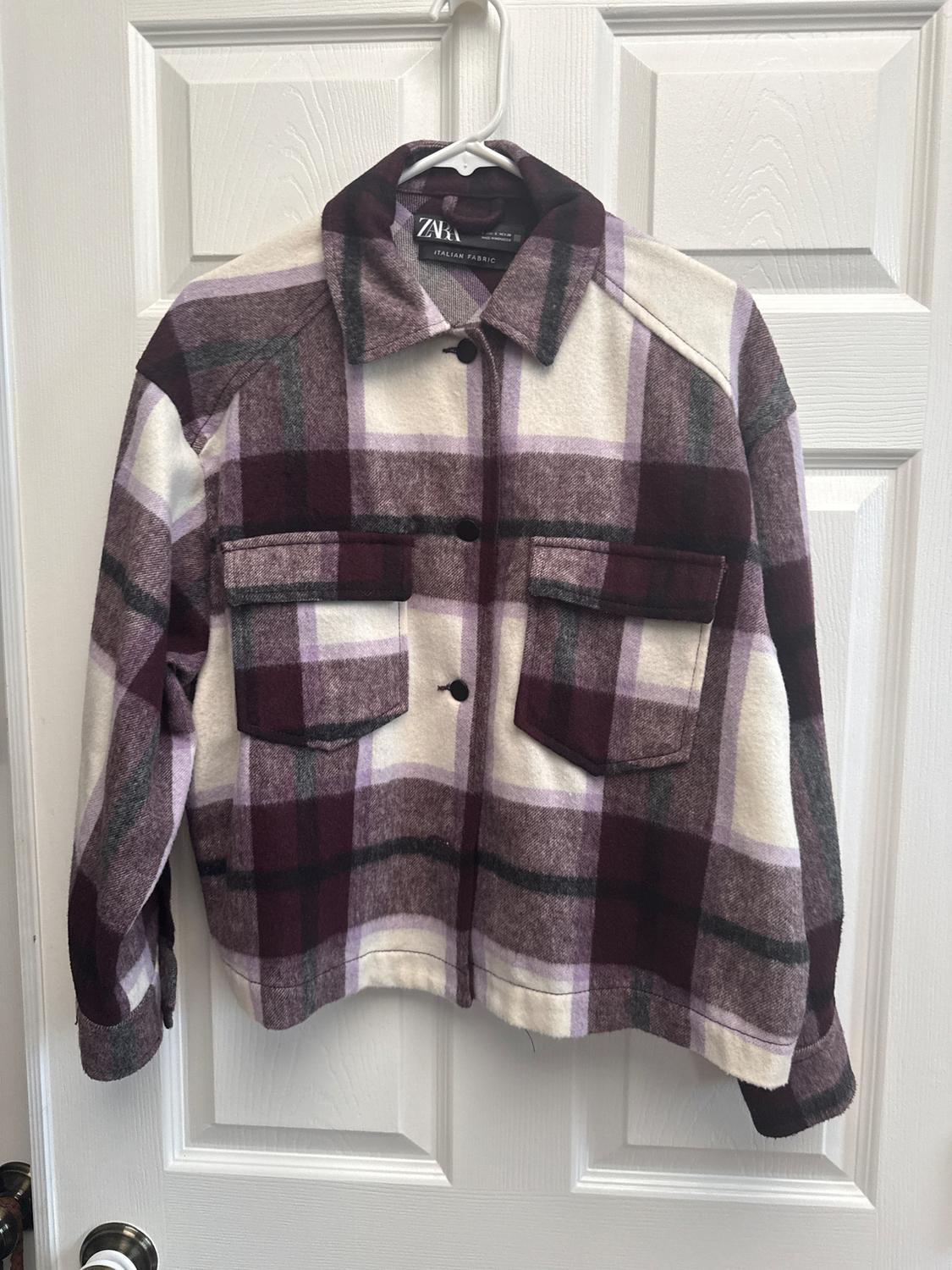 Checked jacket in shades of purple and white with front pockets, hanging on a white door. Visible label: "ZARA ITALIAN FABRIC".