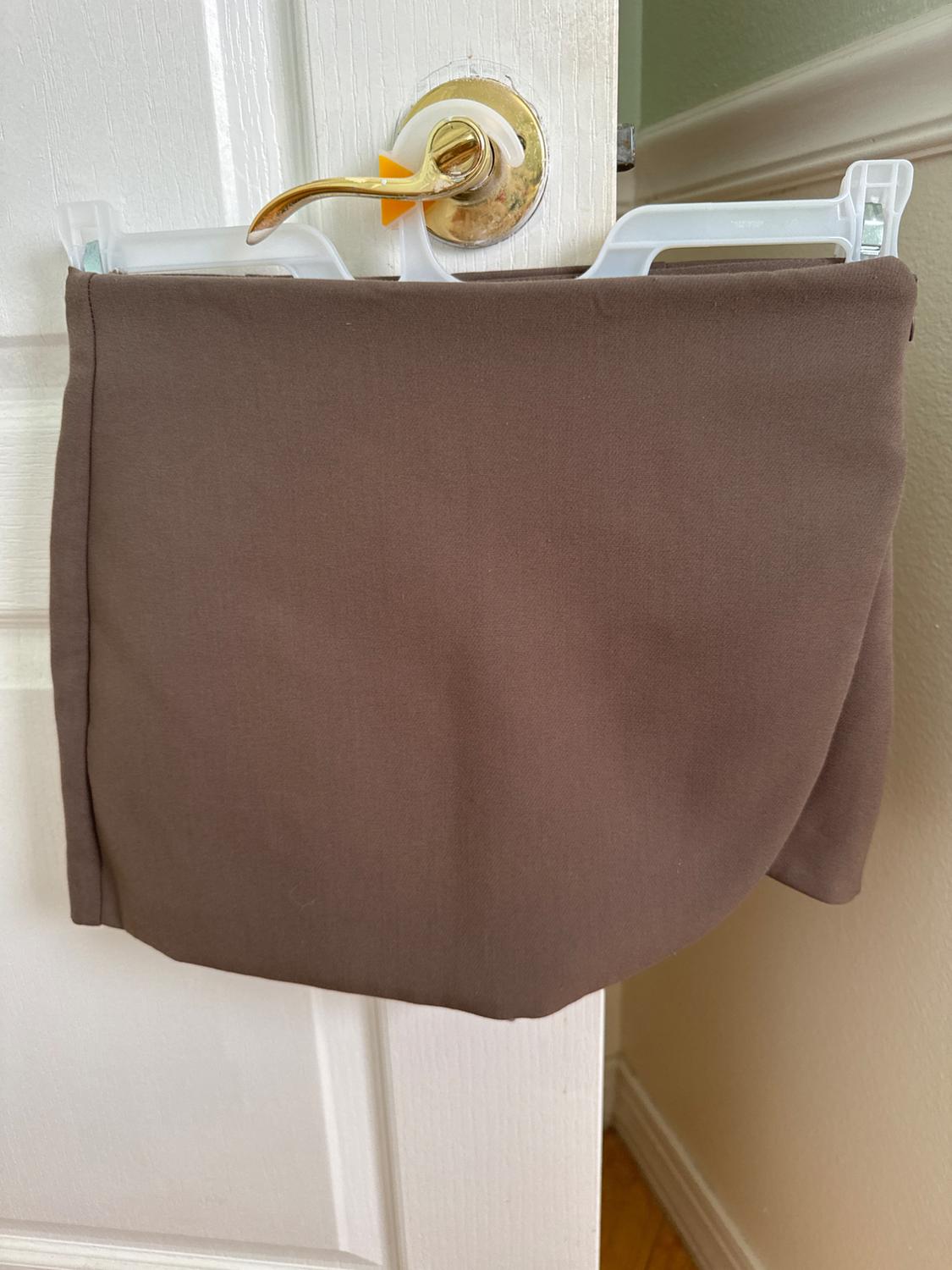 Front view of a brown skirt hanging on a door.
