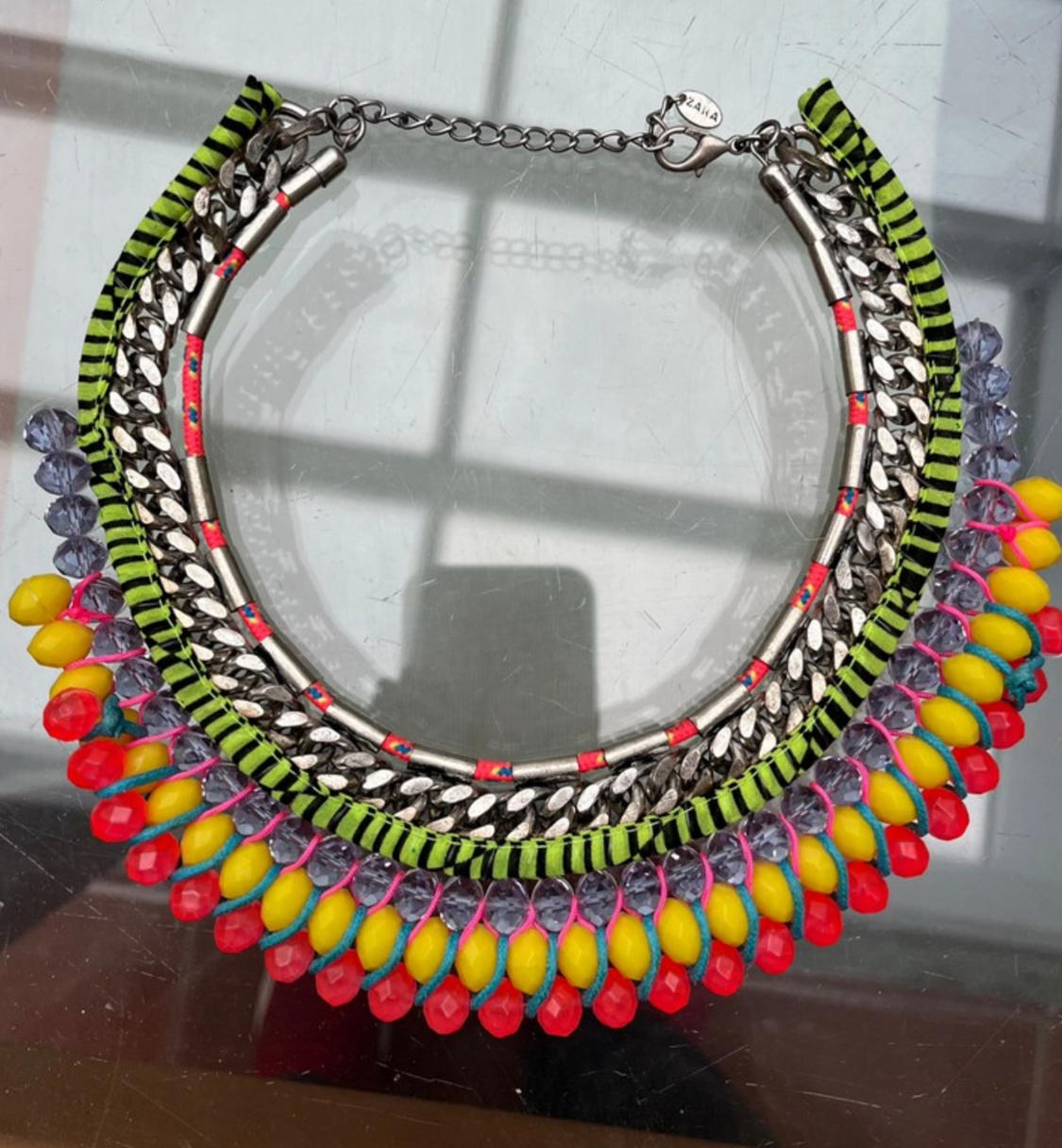 Close-up of a necklace with red, yellow, and purple beads and metallic details.
