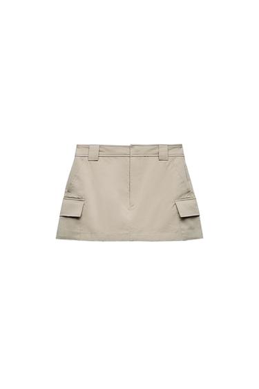 Front view of beige skirt with side flap pockets and belt loops.