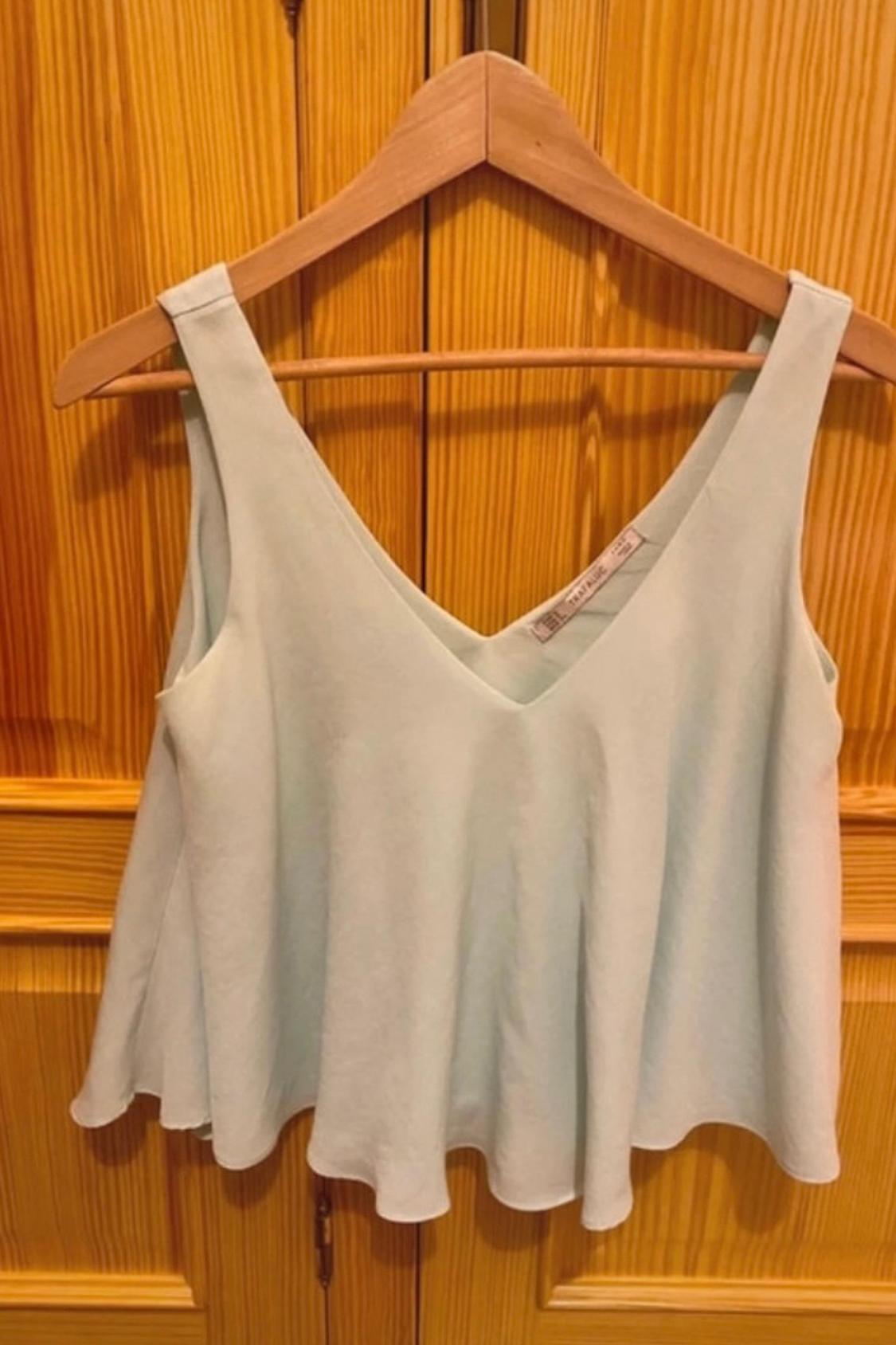 Front view of a light blue sleeveless top with a V-neck, hanging on a hanger.