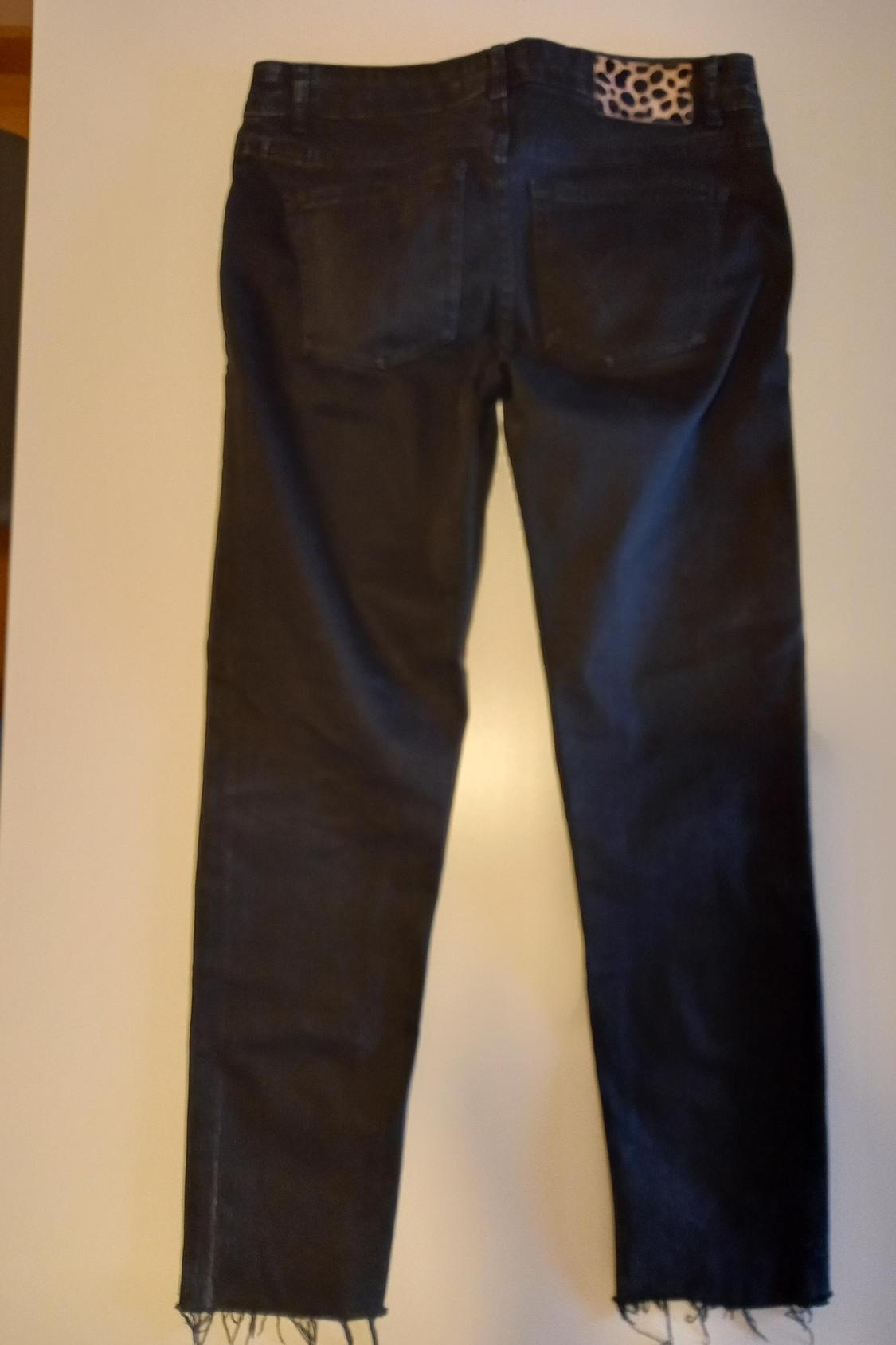 Back view of dark trousers with back pockets and animal print detail on the waist.