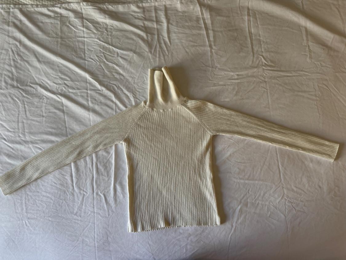 Front view of a white high-neck sweater with long sleeves and a ribbed texture.