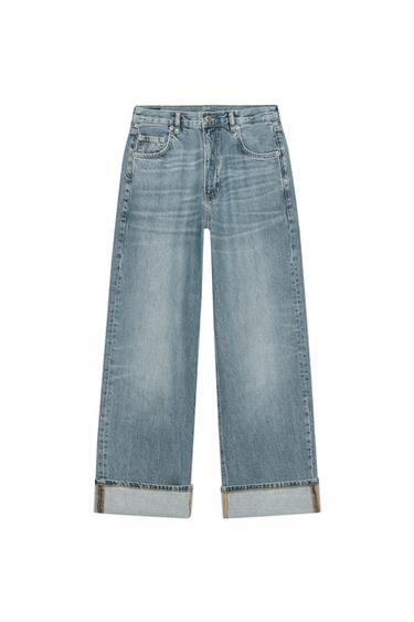 Front view of baggy blue jeans with a faded wash, five pockets and turn-up hems. Front zip and button fastening.