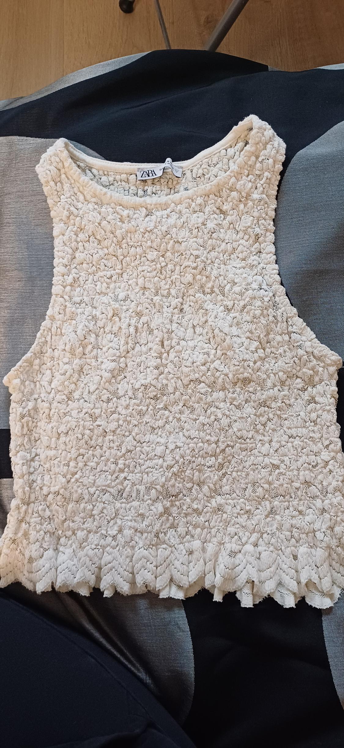 Cream fluffy textured sleeveless top on a black and grey background. Visible label with text "ZARA".
