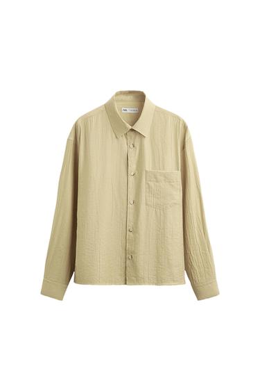 Front view of a beige shirt with a front pocket and full button fastening.