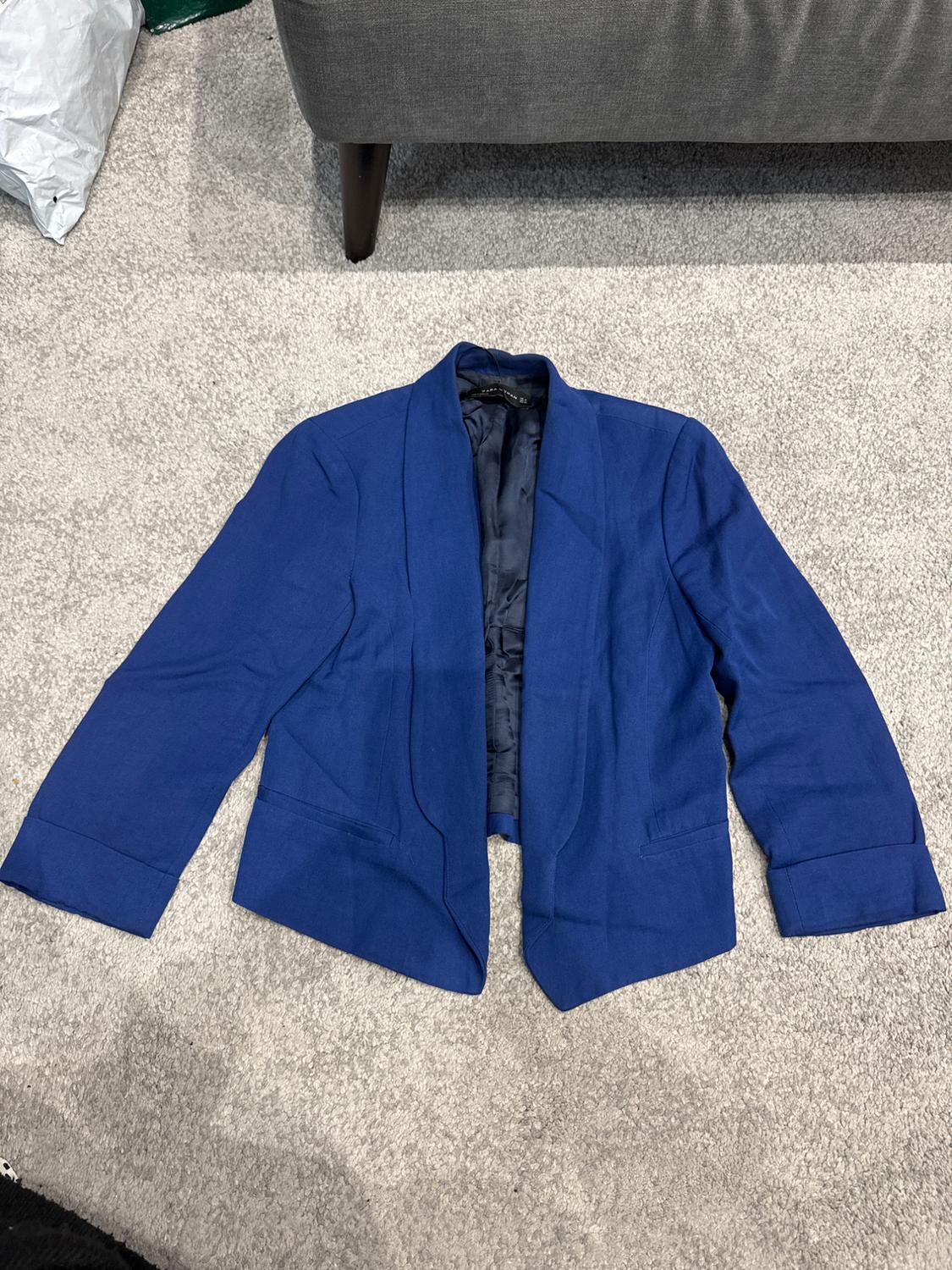 Front view of a blue jacket with wide lapels and side pockets.