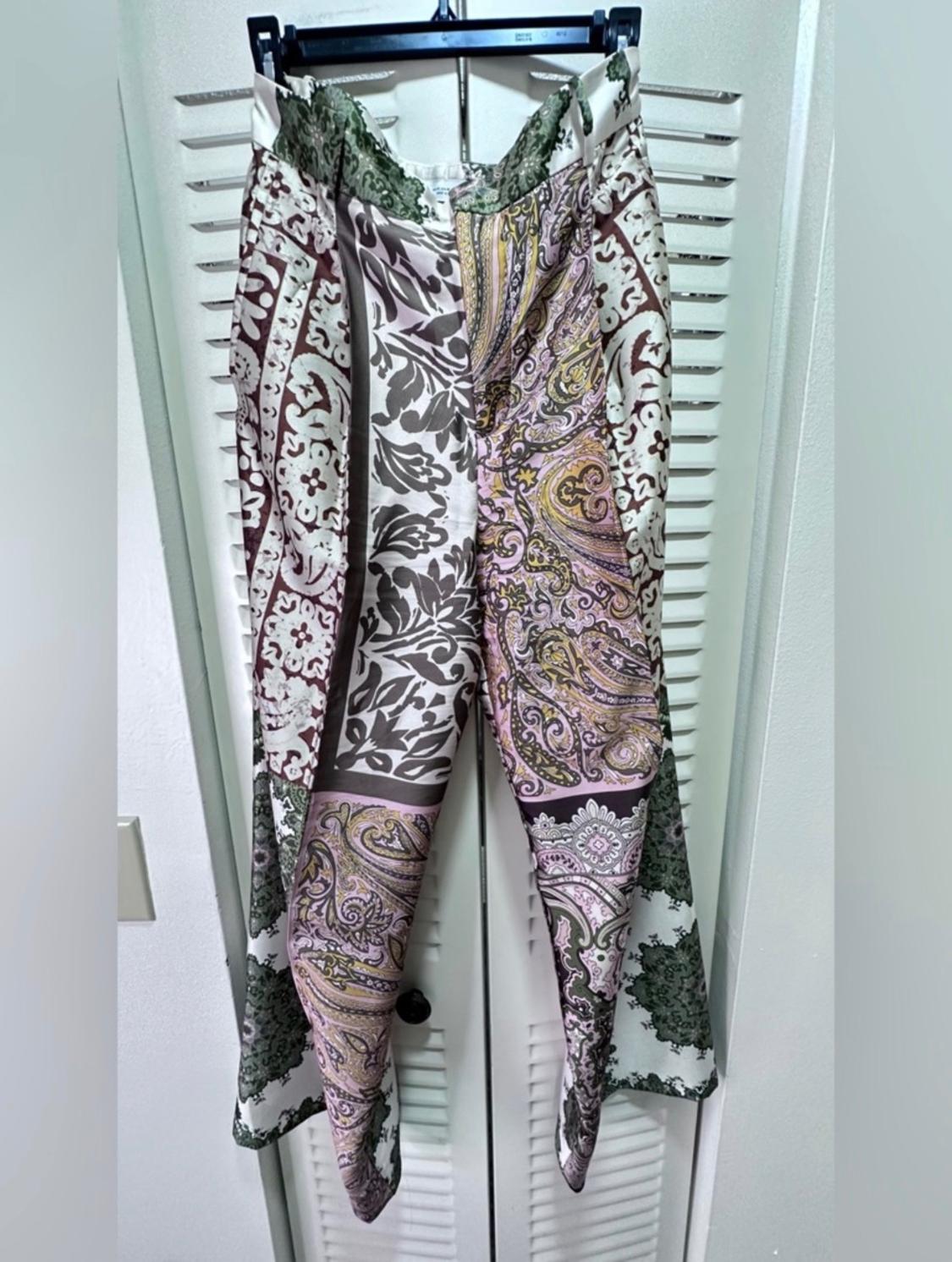 Floral and paisley-print draped trousers in shades of green, purple, and beige, against a backdrop of white doors.