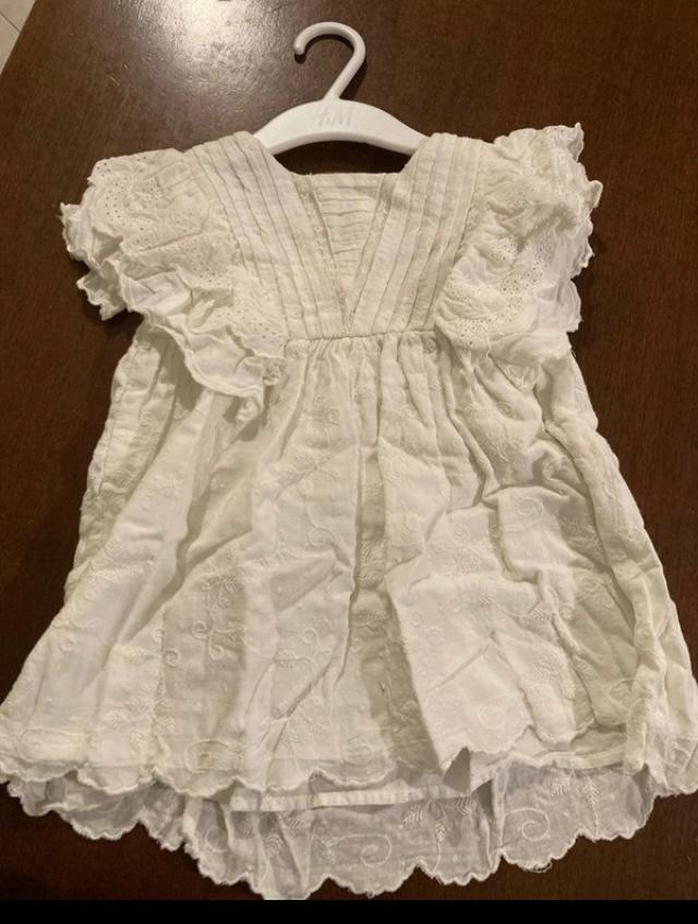Front view of a white dress with short sleeves and floral embroidery.