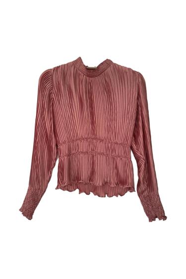Pink pleated long-sleeve blouse with a high neck, smocked waist and cuffs with ruffle detail, on a white background.