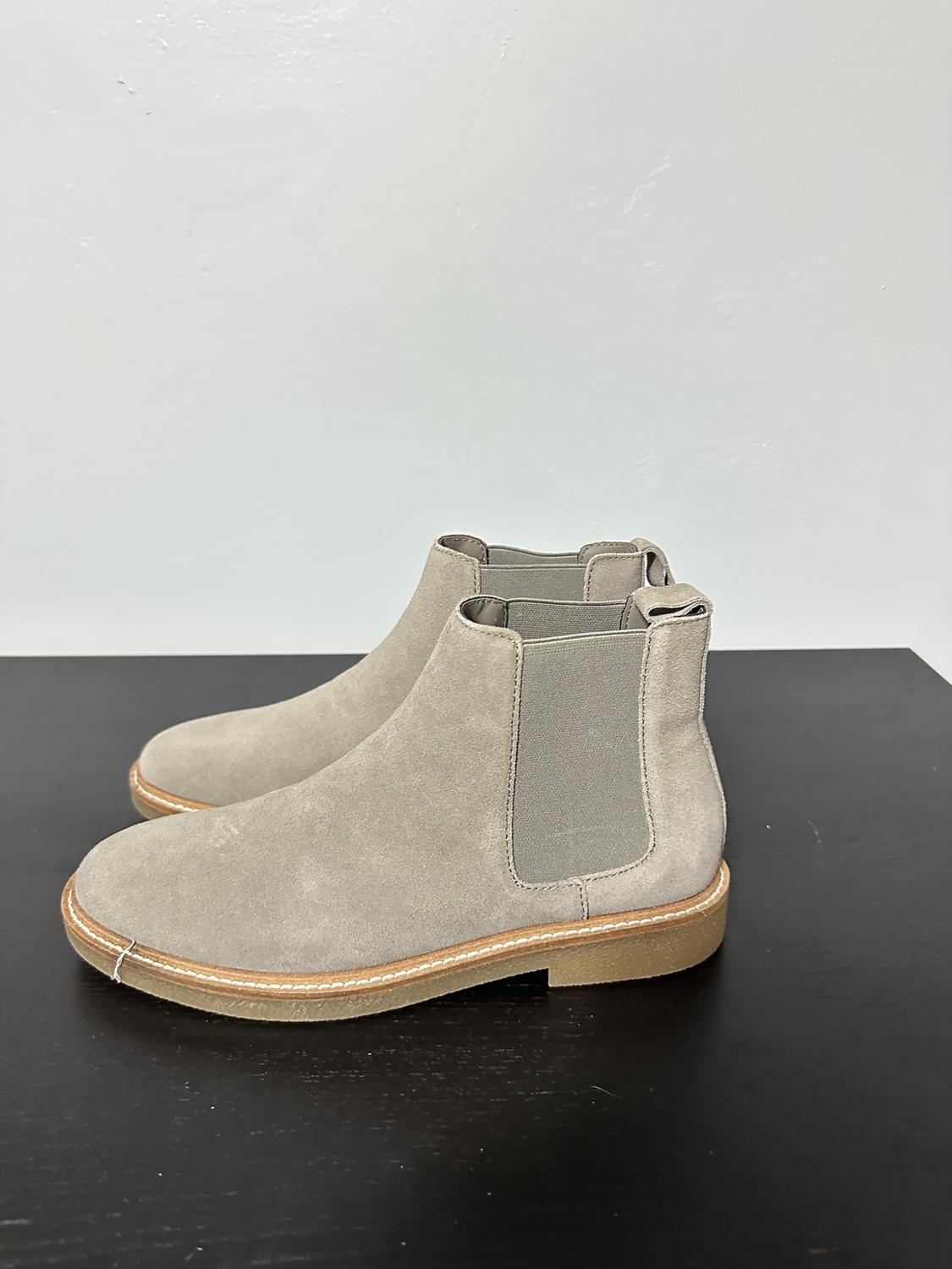 Light grey suede boots with elasticated sides on a black surface. Plain white background.
