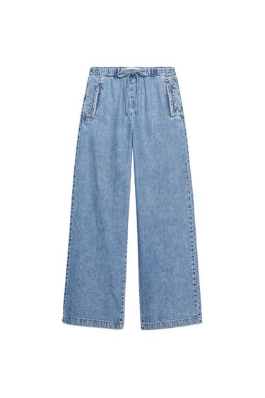 Front view of light blue denim pants with side pockets and drawstring waist.