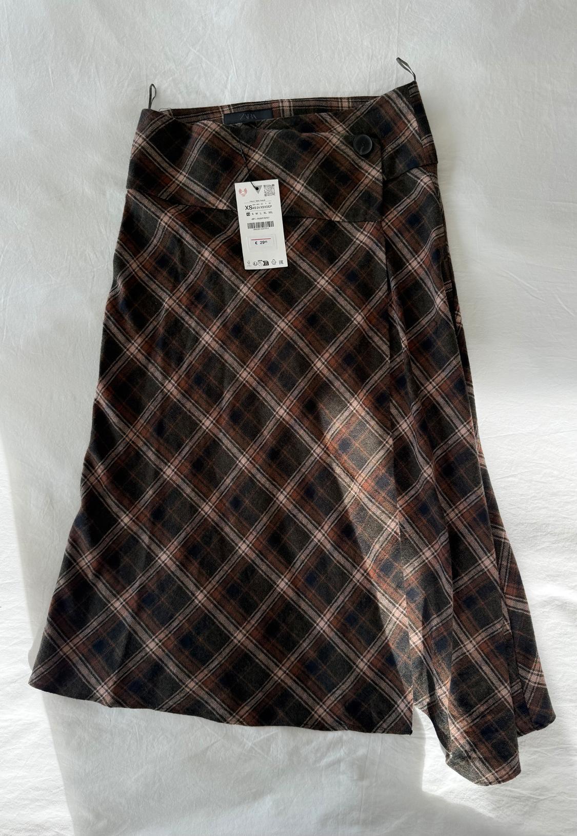 Brown and black checked skirt, hung up, with visible label showing size XS and price of £29.99. White background.