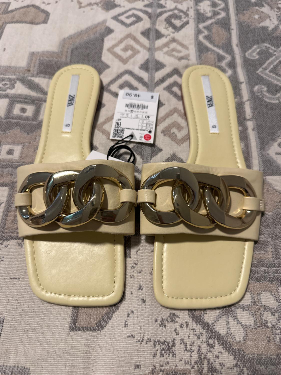 Beige sandals with gold links on geometric patterned fabric. Visible tag with price of $49.90 and size 40.