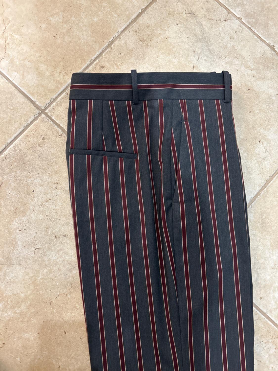 Detail of vertically striped pants with back pockets and belt loops.