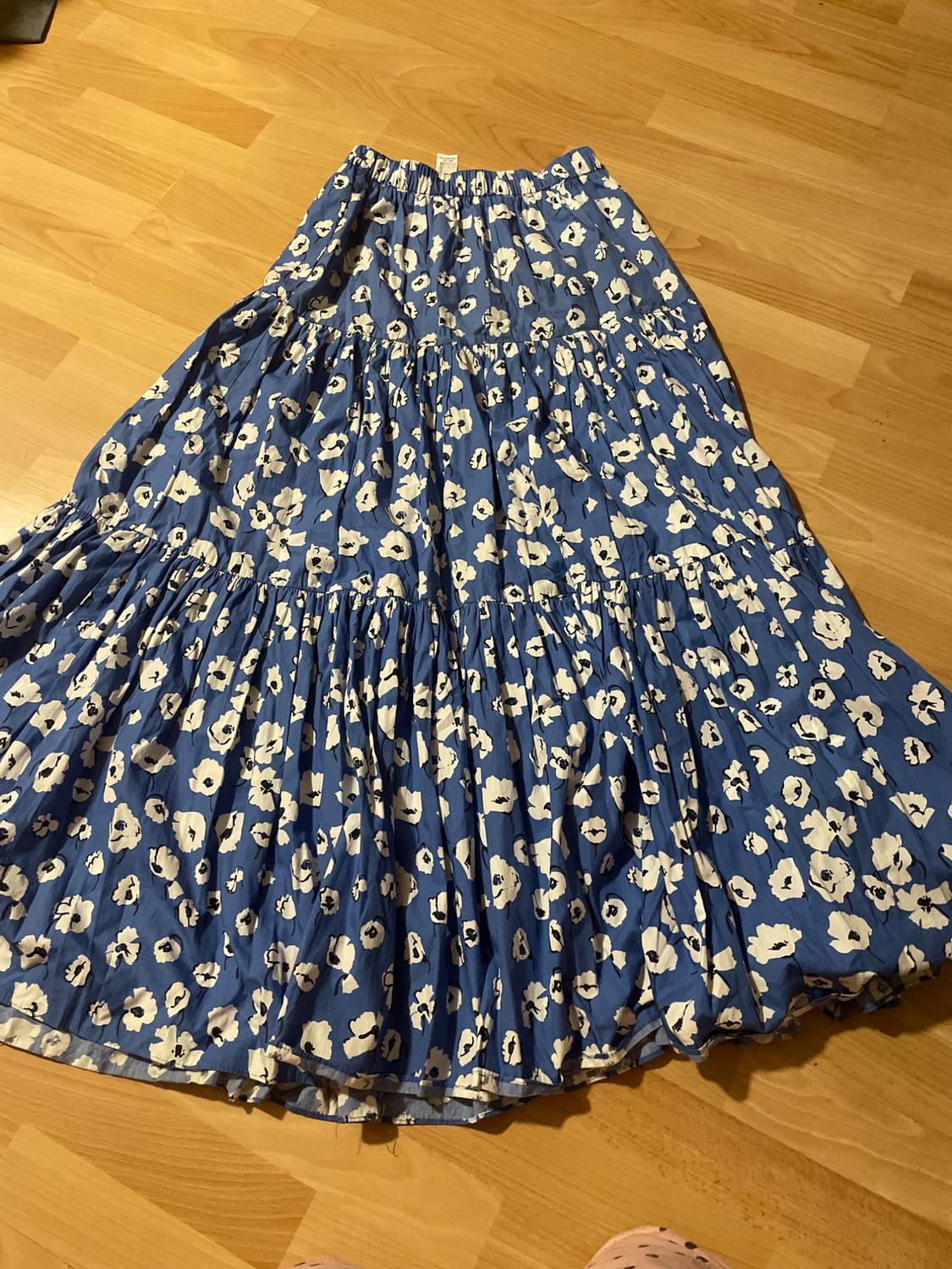 Blue maxi skirt with white floral print on a light wooden floor. Lightweight fabric with pleats and an elasticated waist.