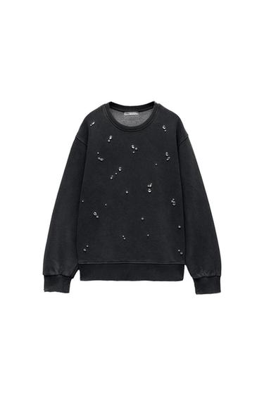 Black sweatshirt with a crew neck and scattered sparkly rhinestone detailing. White background. Visible inner label.