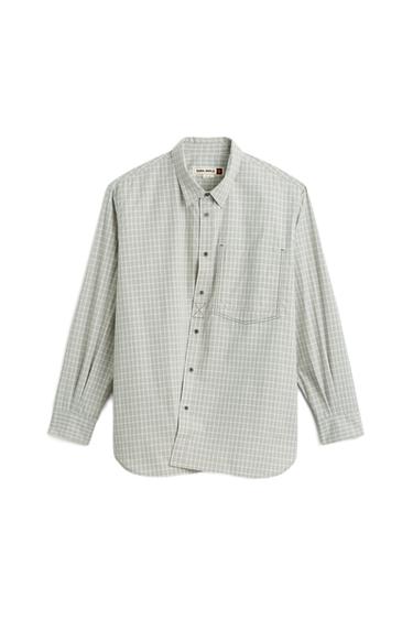 Front view of a checked ecru/khaki shirt, with a lapel collar, long sleeves, patch pocket and asymmetric buttoning.