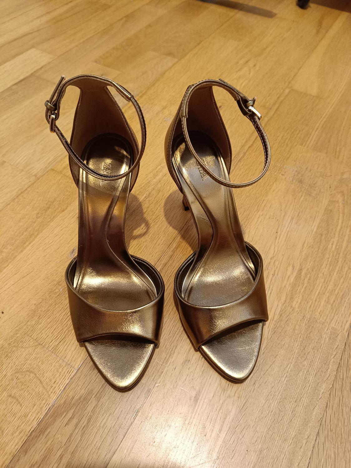 Top view of gold high-heeled sandals with an ankle strap.