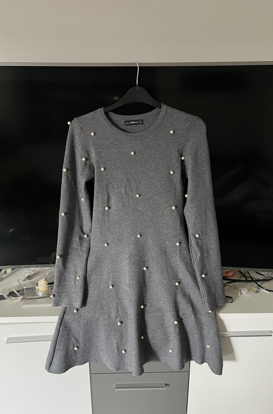 Front view of a grey dress with decorative pearls and long sleeves.