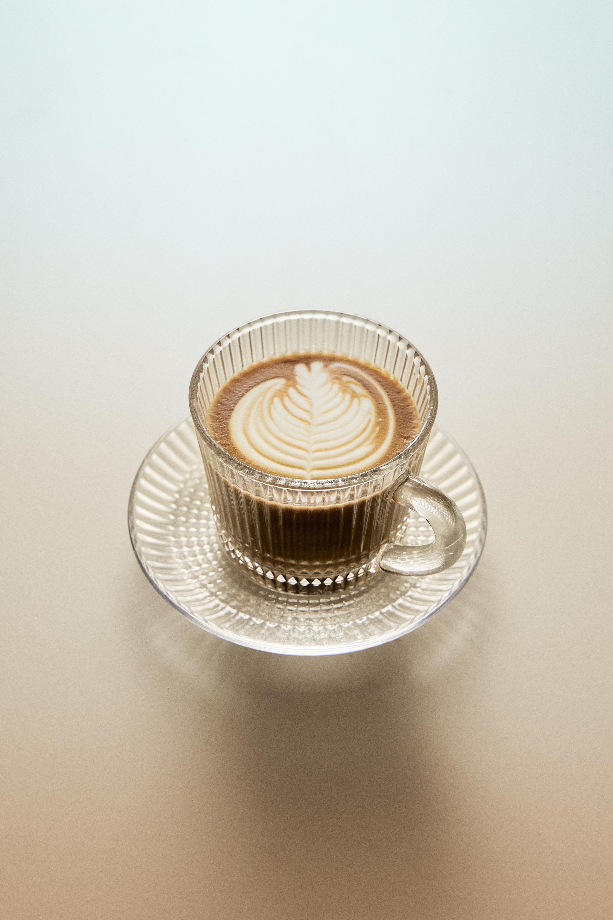 GLASS COFFEE CUP WITH SAUCER AND RAISED GEOMETRIC DESIGN.