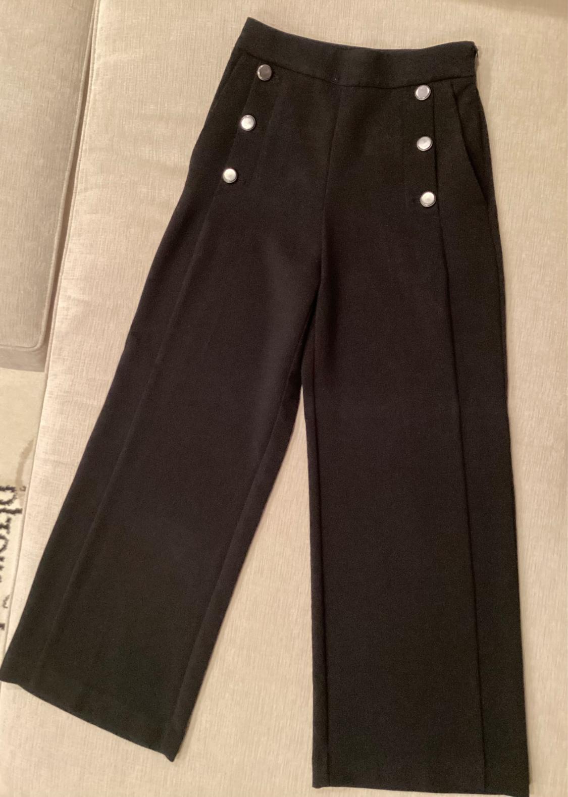 Front view of black pants with silver buttons and side pockets