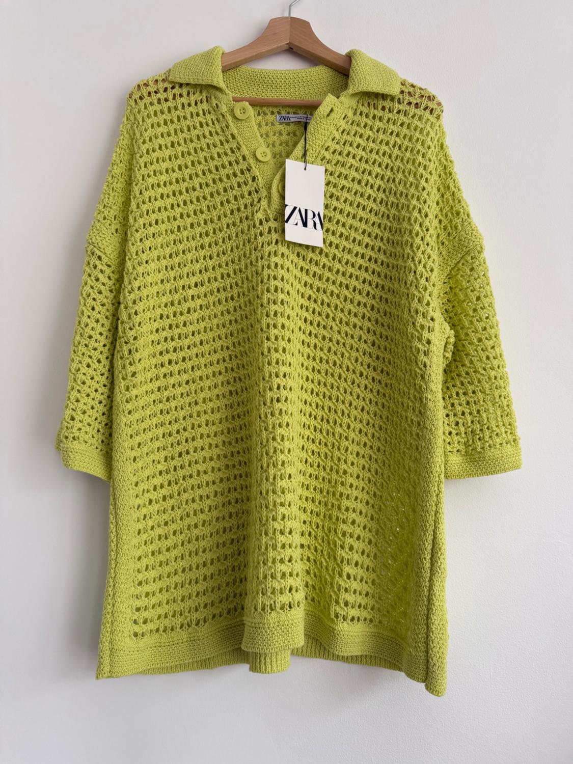Lime green pointelle knit jumper with collar and buttons, hanging on a wooden hanger. Label with text "ZARA".