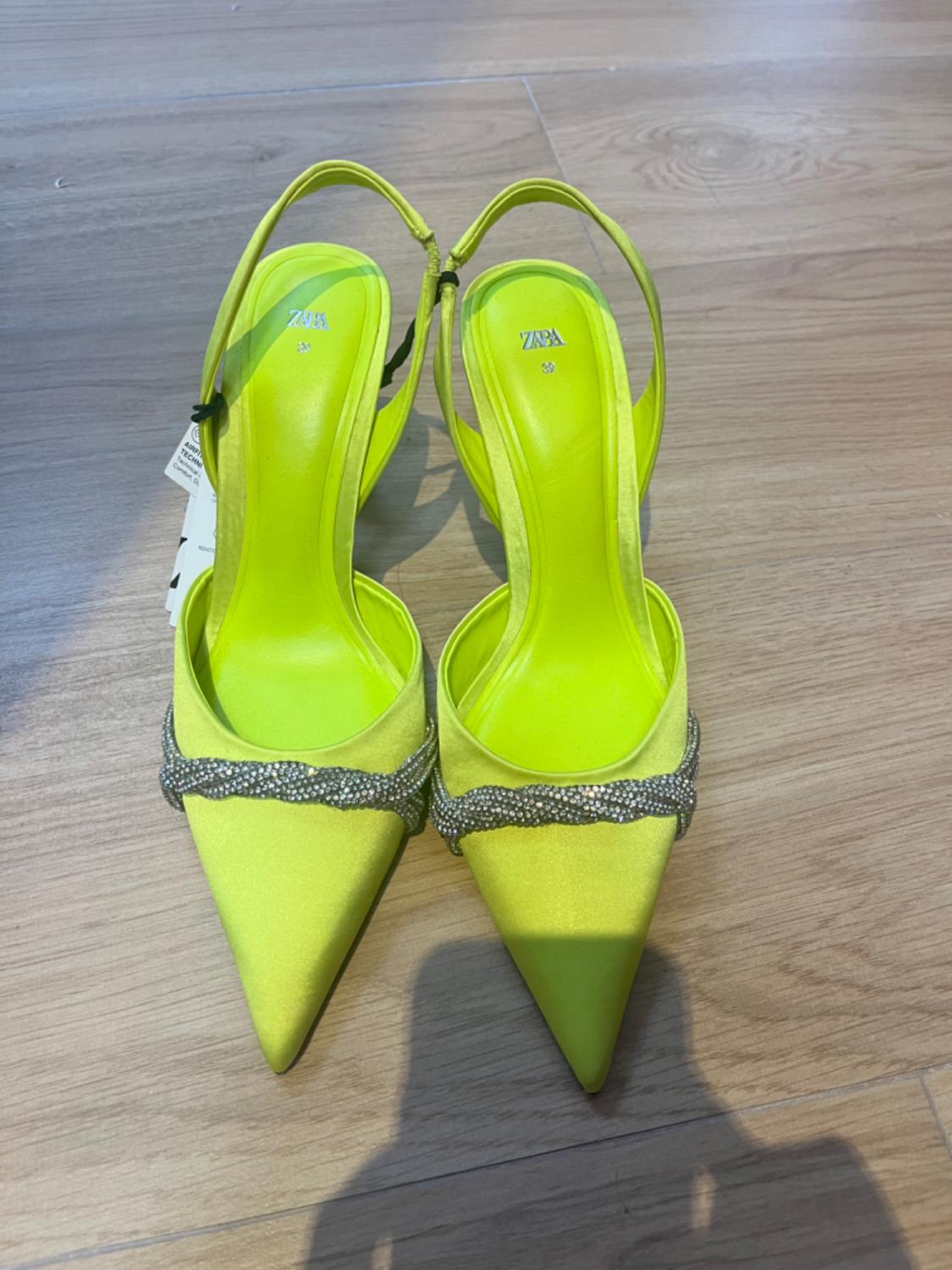 Front view of neon green stiletto heels with a pointed design and sparkling decorative details.