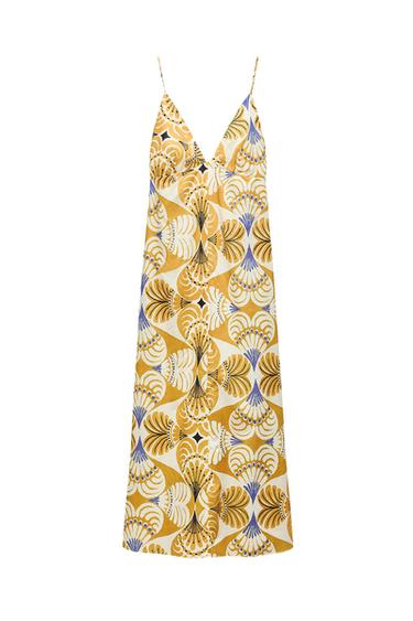 Long dress with thin straps and a V-neckline, featuring a geometric print in mustard, white, and blue tones on a white background.
