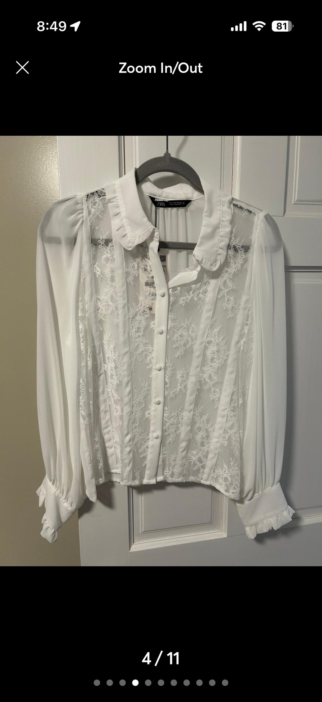 White lace blouse with long puff sleeves and front buttons, hanging on a hanger in front of a white door.