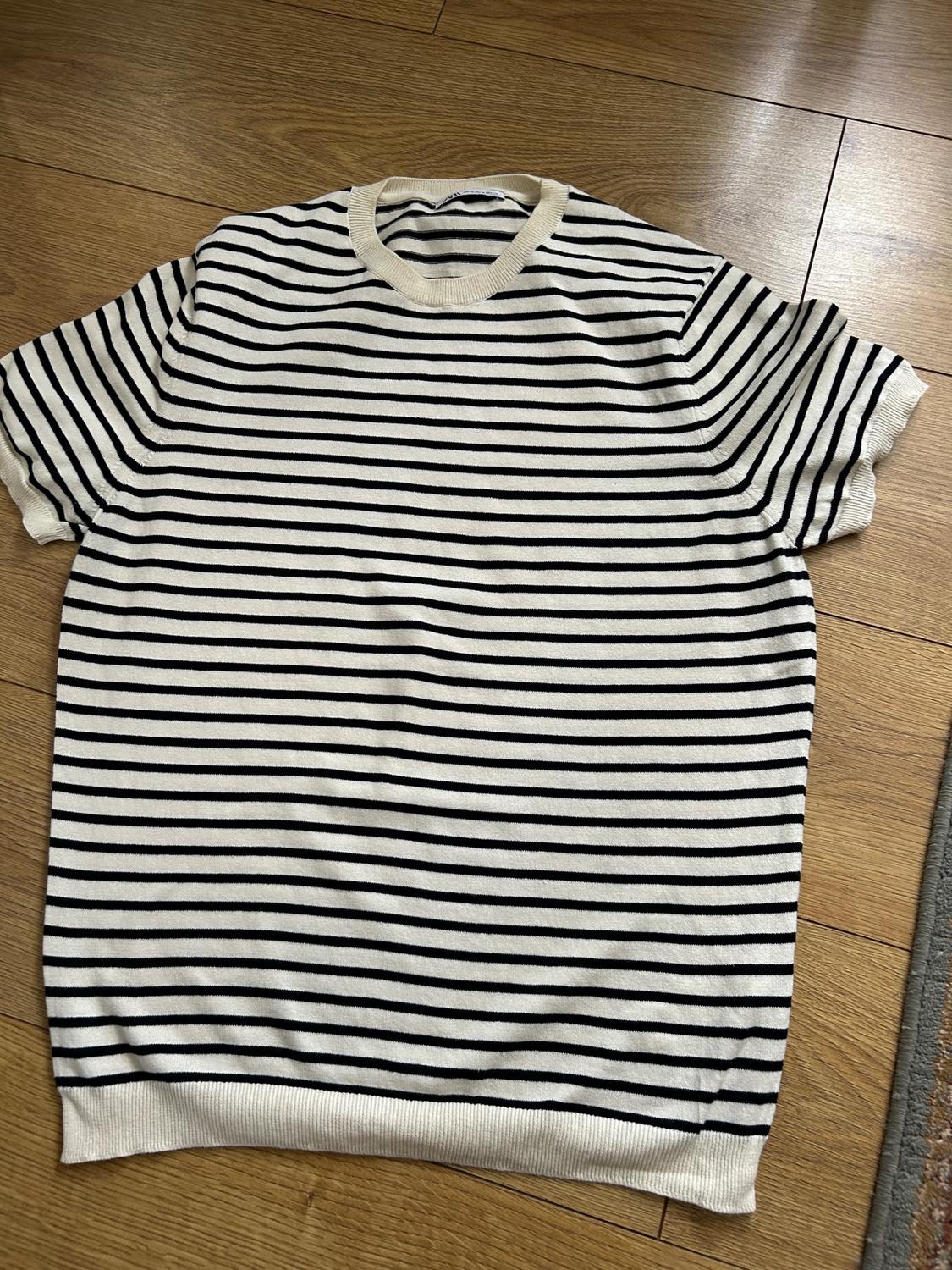 Black and white horizontal striped T-shirt on a wooden floor. Short sleeves and a round neck.