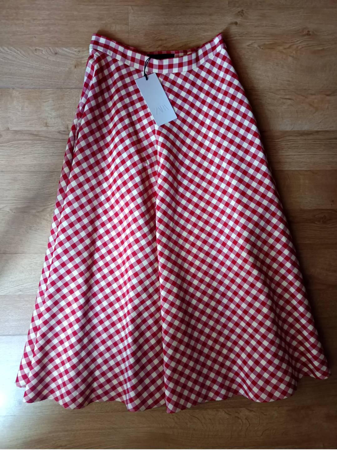 Red and white checked maxi skirt on a wooden floor. Label with the text ZARA.