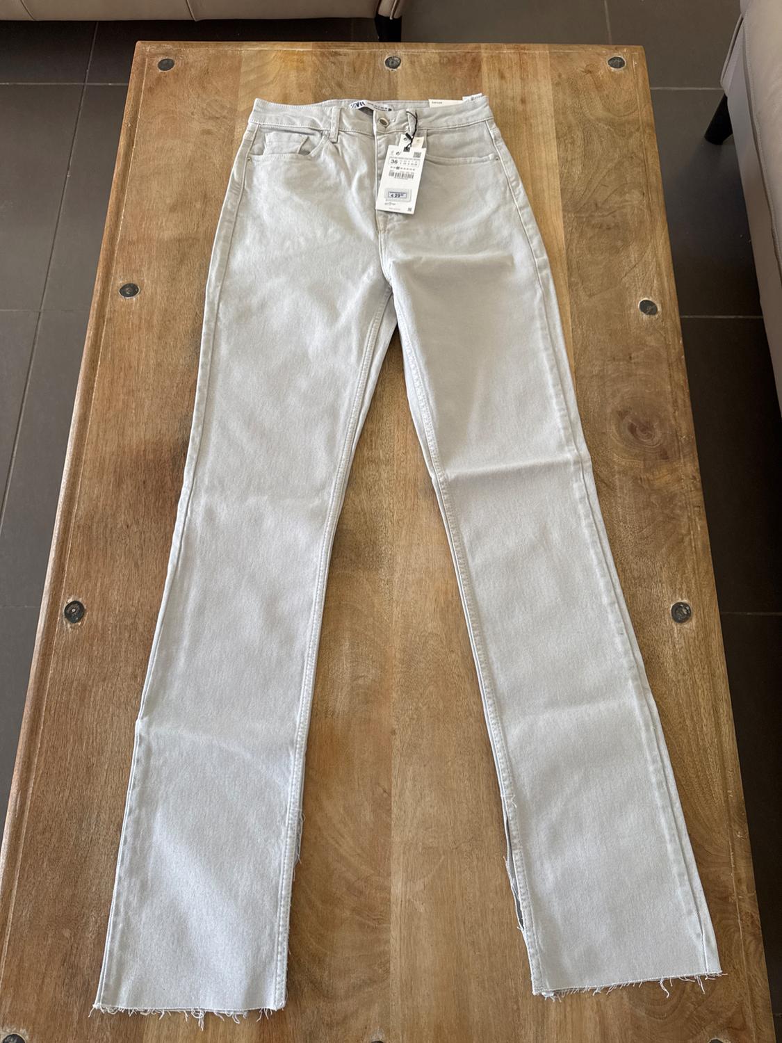 Light-wash jeans with a hang tag, placed on a wooden table.