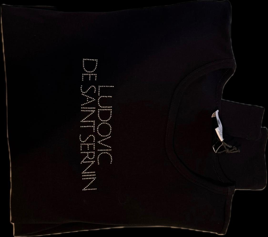 Folded black t-shirt with the vertical text "LUDOVIC DE SAINT SERNIN" in sparkling rhinestones and a visible neck label.