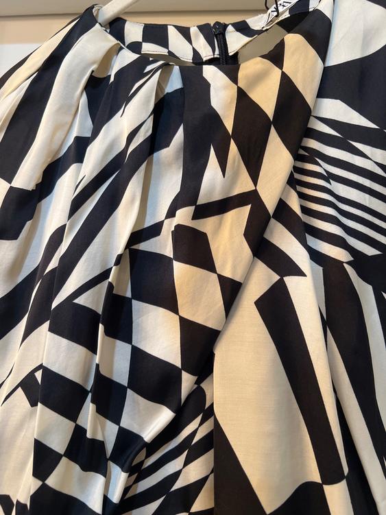 Black and white geometric print fabric, with pleats and a visible zipper closure at the top.