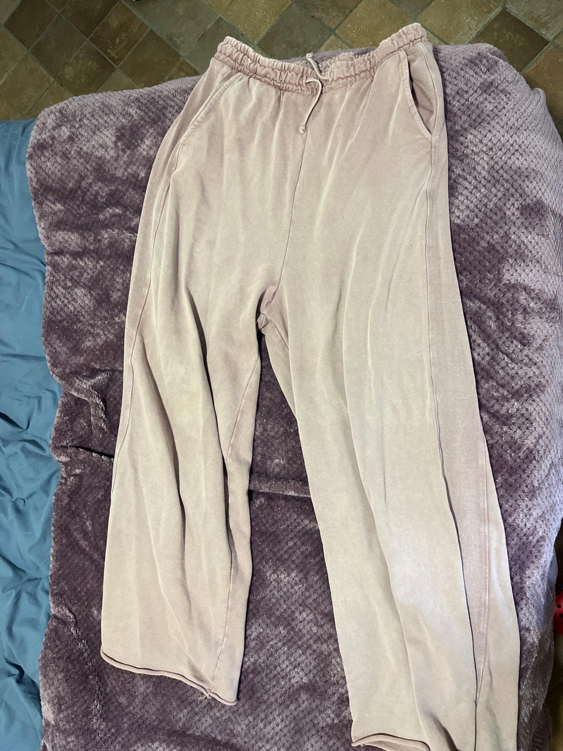 Light beige joggers with an elasticated drawstring waist, laid on a textured purple and blue blanket.