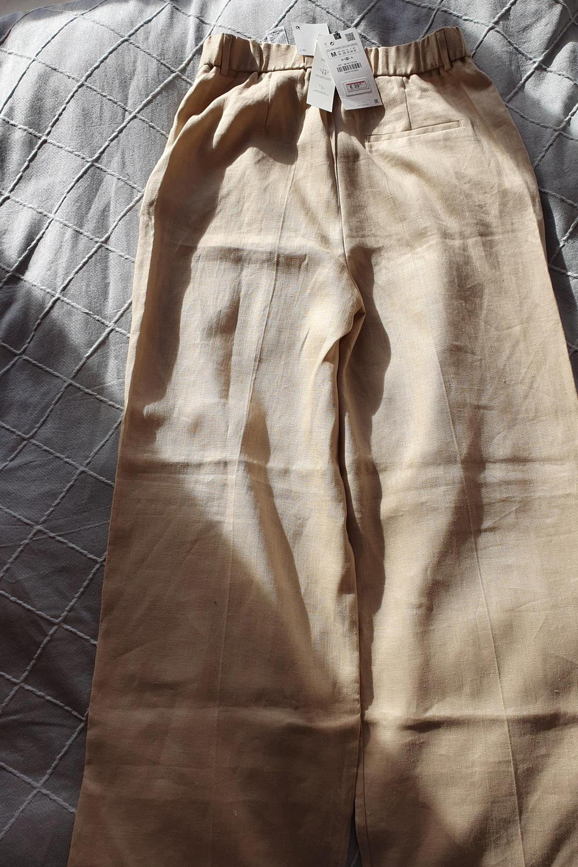 Front view of beige trousers with elasticated waistband and back pocket.