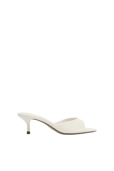 White low-heeled slingback shoe with an open toe. Side view against a minimalist white background.
