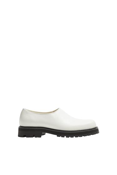 Side view of a white shoe with a black sole and a simple design.