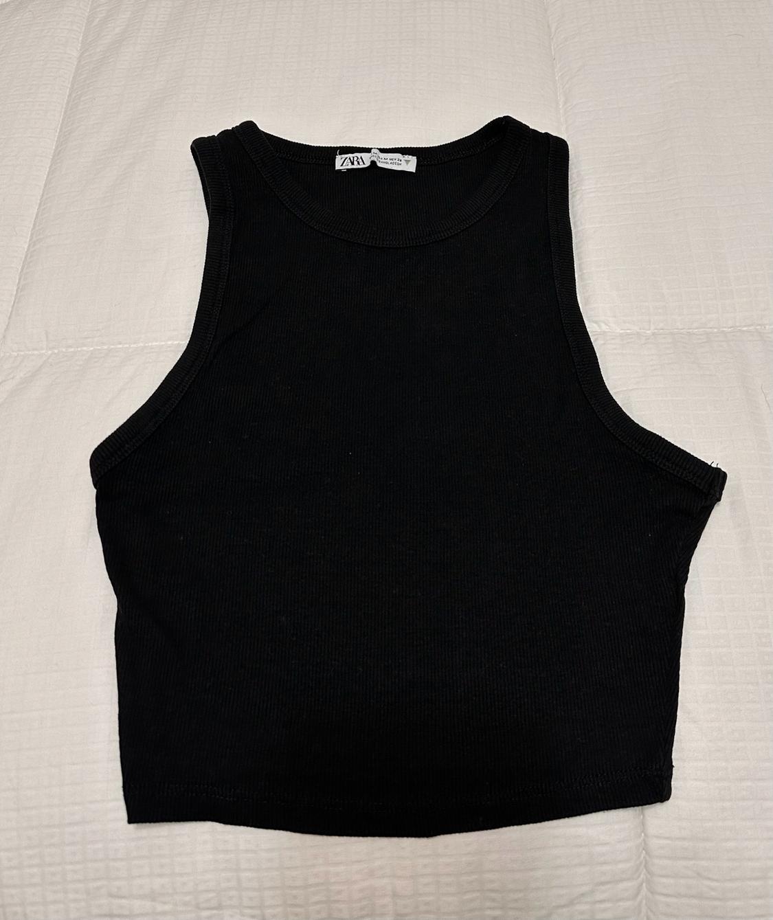 Black sleeveless ribbed crop top on a padded white surface. Label with the text ZARA.