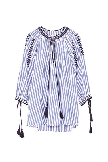 Blue and white vertically striped blouse with embroidery on the collar and sleeves. Features drawstring ties with tassels on the neckline and cuffs on a white background.