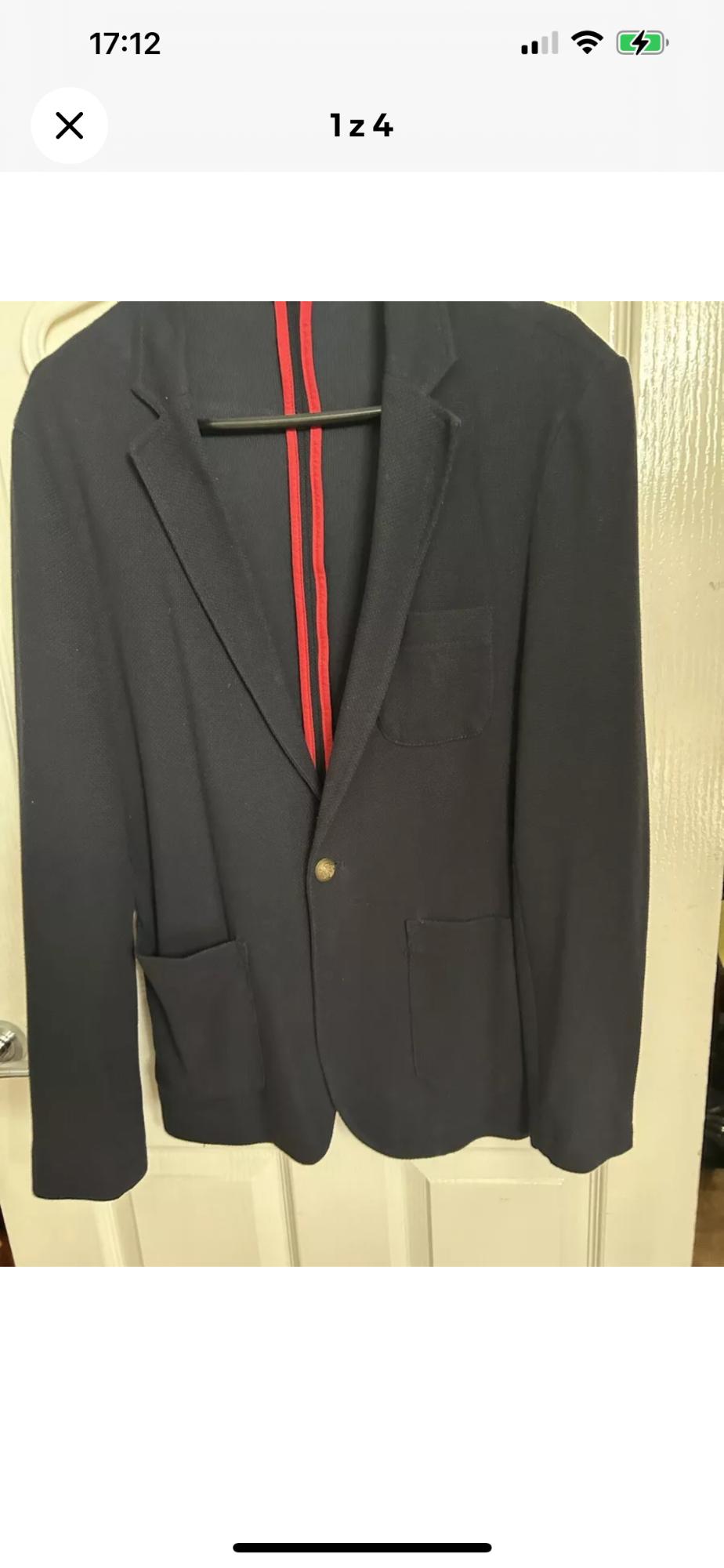 Front view of a blue jacket with a gold button and front pockets.