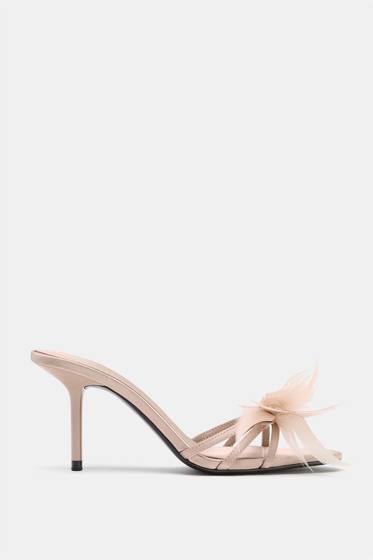 Side view of a pastel pink slingback sandal with a high stiletto heel, front straps, and feather detailing.