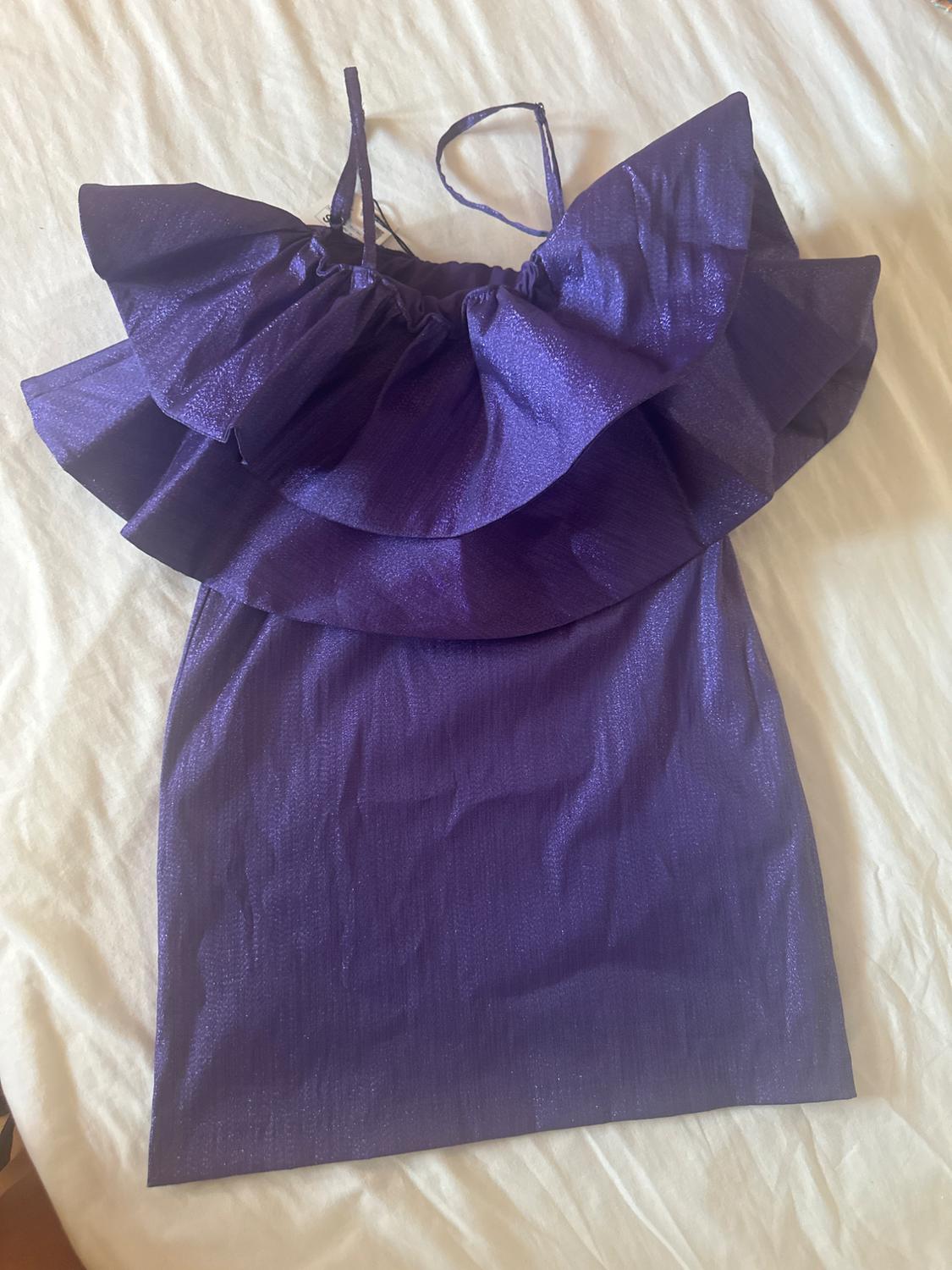Purple dress with large frills at the top, thin straps, on a white surface.